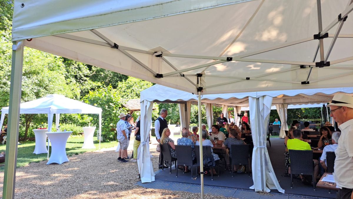 Outdoor-Veranstaltung bei sonnigem Wetter mit Pavillons und Gästen.